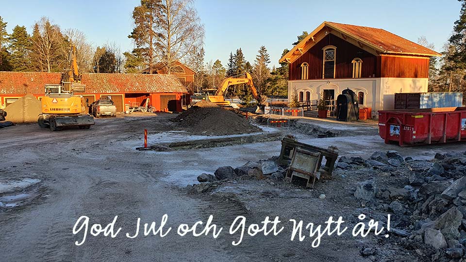 Foto över centrala gruvområdet vid Sala Silvergruva, marken är täckt med lite snö, på bilden syns schakt och en grävmaskin, över fotot står det God Jul och Gott Nytt År